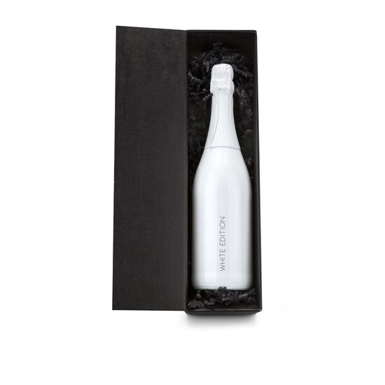 Weiß lackierte Flasche Cuvée Sekt (0,75 l) mit Druck „White Edition“, gebettet auf schwarzem Sizzle und verpackt im schwarzen Präsentkarton.