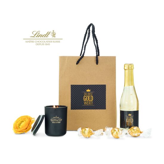 Die Tüte ist gefüllt mit "Du bist Gold wert" Secco (0,2 L), 3 goldenen Lindt Lindor Kugeln und einer ROMOSCENT® Sparkling Gold Duftkerze.